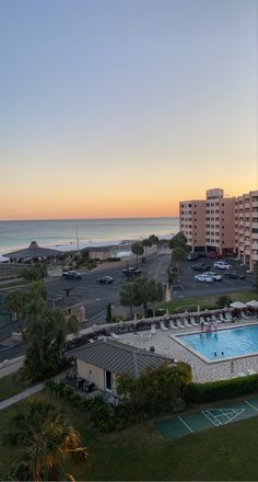 an aerial view of the pool and beach at sunset or sunrise, with apartment buildings in the background