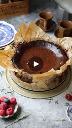 a chocolate cake sitting on top of a table next to plates and bowls filled with raspberries