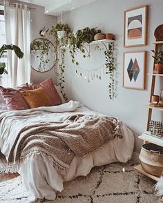 a bedroom with white walls and plants hanging on the wall above the bed, along with other decor