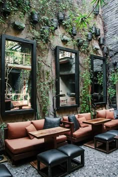 an outdoor seating area with mirrors and plants on the wall