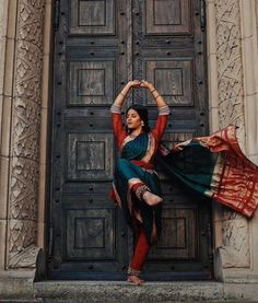 a woman standing in front of a wooden door with her arms stretched out to the side