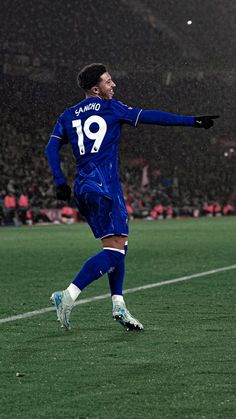 a soccer player is running on the field with his arms out and one foot in the air