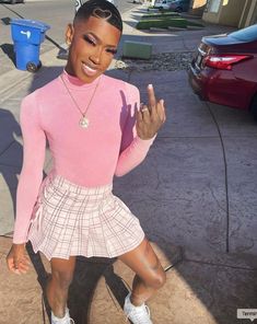 a woman in pink shirt and skirt standing on sidewalk