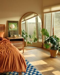 a bed room with a neatly made bed and lots of plants on the windowsill