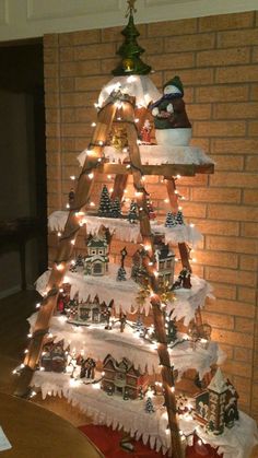 a christmas tree made out of snow with lights and ornaments on it in front of a brick wall