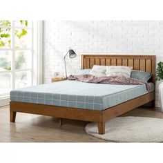 a bed with a wooden headboard and foot board in a white brick walled room