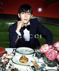 a man in a tuxedo sitting at a table with food and drinks on it