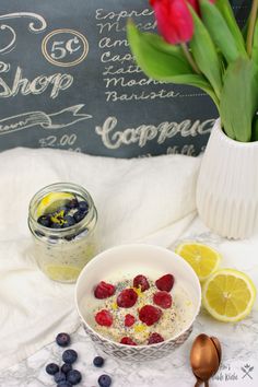 a bowl of oatmeal with berries and blueberries next to a jar of lemonade