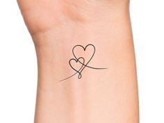 a small tattoo on the wrist of a woman's arm with two hearts in it