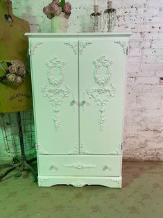 a green armoire sitting in front of a white brick wall