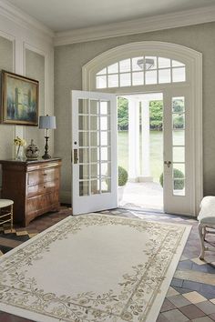 a large rug in the middle of a living room with french doors leading to an outside patio