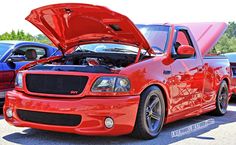 a red car with its hood open in a parking lot