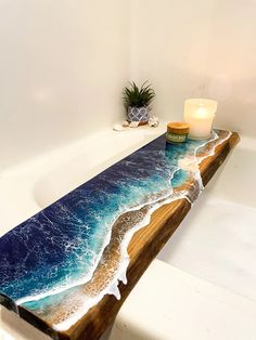 a bath tub with a wooden table that has an ocean scene painted on the side