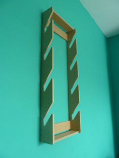 a wooden shelf mounted to the side of a blue wall with a ladder on it