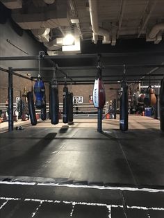 an empty boxing ring with punching gloves hanging from the ceiling and other equipment on the ground