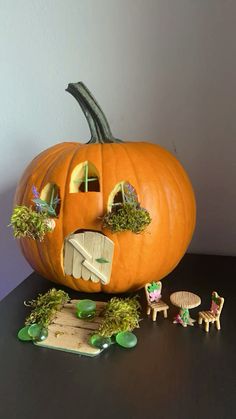 a pumpkin with an open mouth and two small figurines next to it on a table