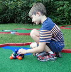 a young boy playing with balls in the grass