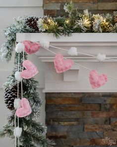 a fireplace mantel decorated for christmas with pink and white hearts hanging from the mantle