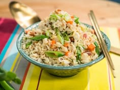 a bowl filled with rice and vegetables next to chopsticks