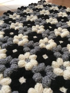 a black and white crocheted blanket on the floor