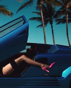 a woman sitting in the back of a blue car with her legs out and wearing high heels