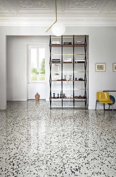 an empty room with white walls and flooring is pictured in this image, there are two yellow chairs on the far side of the room