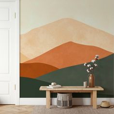 a table with vases and flowers on it in front of a wall mural that looks like mountains