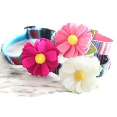 three flower bracelets sitting on top of a marble counter