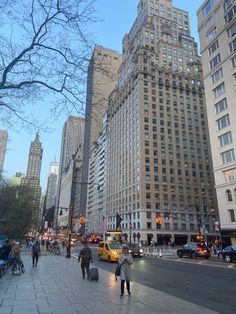 people are walking down the street in front of tall buildings