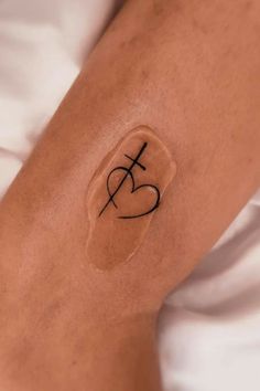 a woman's arm with a tattoo that has the letter f on it and a heart