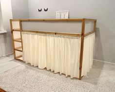 a white curtained bed with a wooden frame on the top and bottom, in a bedroom