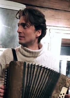 a man is holding an accordion in his right hand and looking at the other side