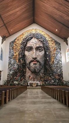 the inside of a church with an image of jesus on it's wall and pews