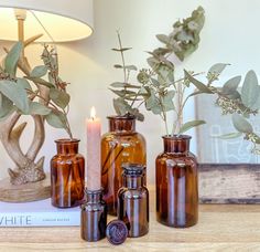 vases and candles are sitting on a table next to a book with a candle in it