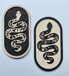 two wooden plaques with black and white designs on them, one depicting a snake and the other featuring stars