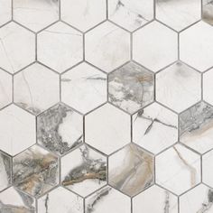 a white marble hexagonal tile pattern with grey and gold details on it's edges