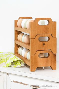 a wooden rack with several eggs in it on top of a white shelf next to a green towel