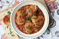 a white bowl filled with meat covered in sauce