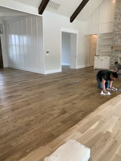 two people in an empty room with hard wood flooring on the ground and walls