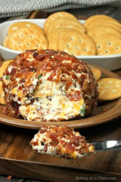 a cheese ball on a plate next to crackers and a bowl of crackers