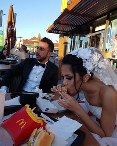 a man and woman sitting at a table with food in front of them on their wedding day