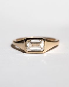 an engagement ring with a baguette cut diamond set in the center, on a white surface