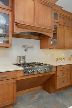 a kitchen with wooden cabinets and white counter tops, including an oven hood over the stove