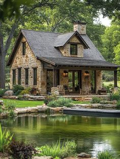 a stone house with a pond in the foreground and trees around it, surrounded by greenery