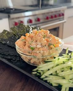 a glass bowl filled with food sitting on top of a black tray next to sliced celery