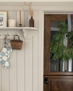 there is a christmas stocking hanging on the wall next to a wreath and other decorations