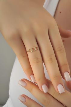 a woman's hand with a gold ring on top of her finger and nails