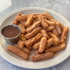 a white plate topped with churros next to a dipping sauce