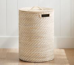 a large woven laundry basket sitting on top of a wooden floor next to a wall