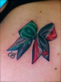 a woman's back with a bow tattoo on her shoulder and the number eight